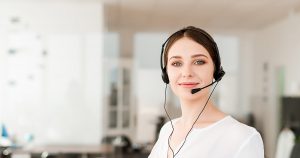 Customer support female employee wearing headphone and facing the camera